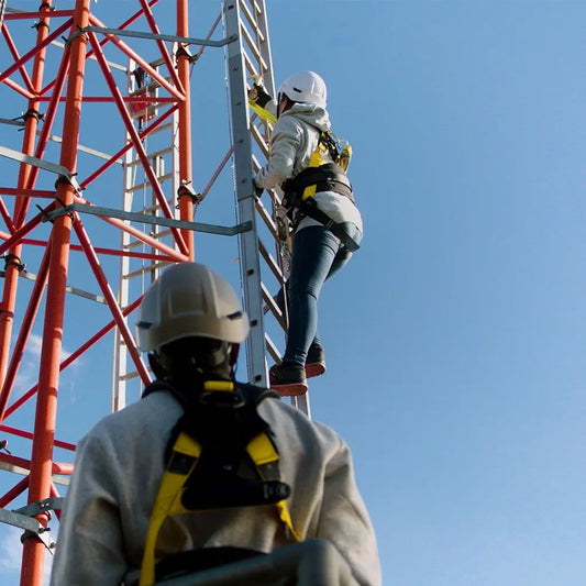 Worker climbing a tower with safety gear on.