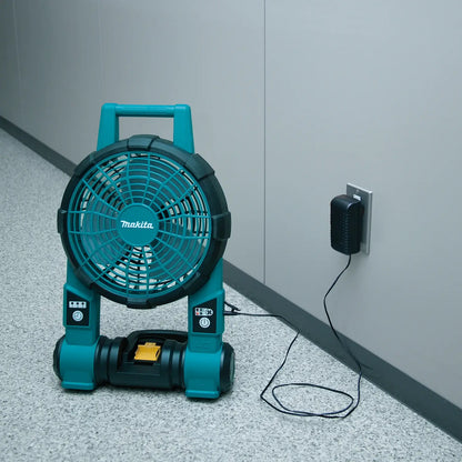 Makita portable fan plugged into an outlet on a concrete floor.