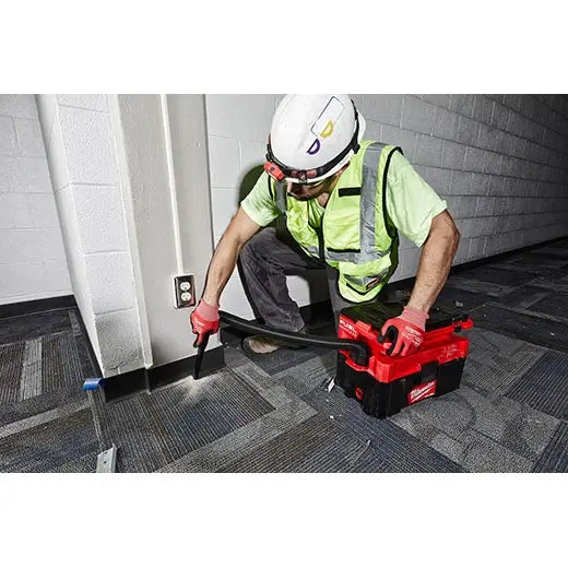 Person in safety gear using a Milwaukee tool box in an indoor setting.