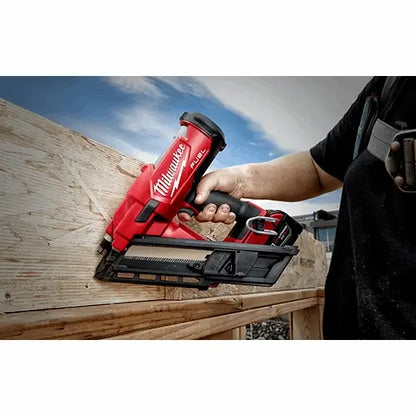 Person using a Milwaukee nail gun on a wooden surface with a blue sky in the background