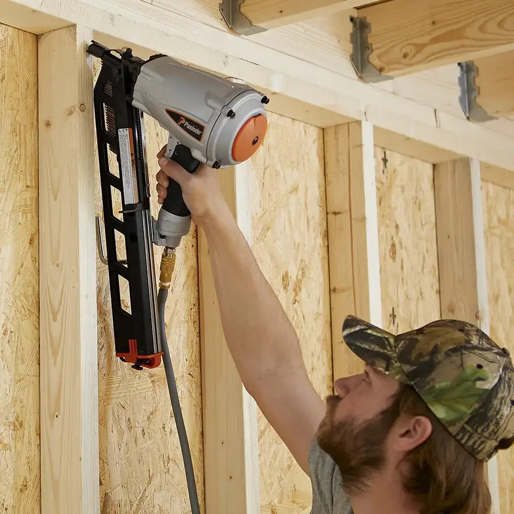 Person using a nail gun on wooden framing