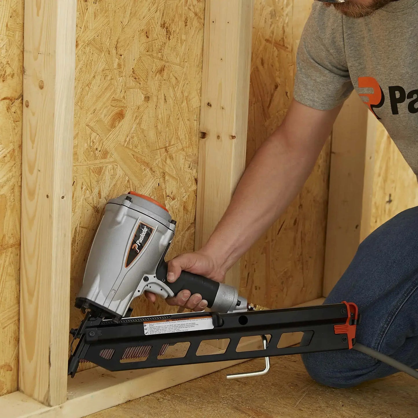 Person using a nail gun on a wooden wall