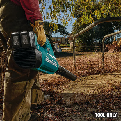 Person using a Makita leaf blower in an outdoor setting with trees and a fence in the background.