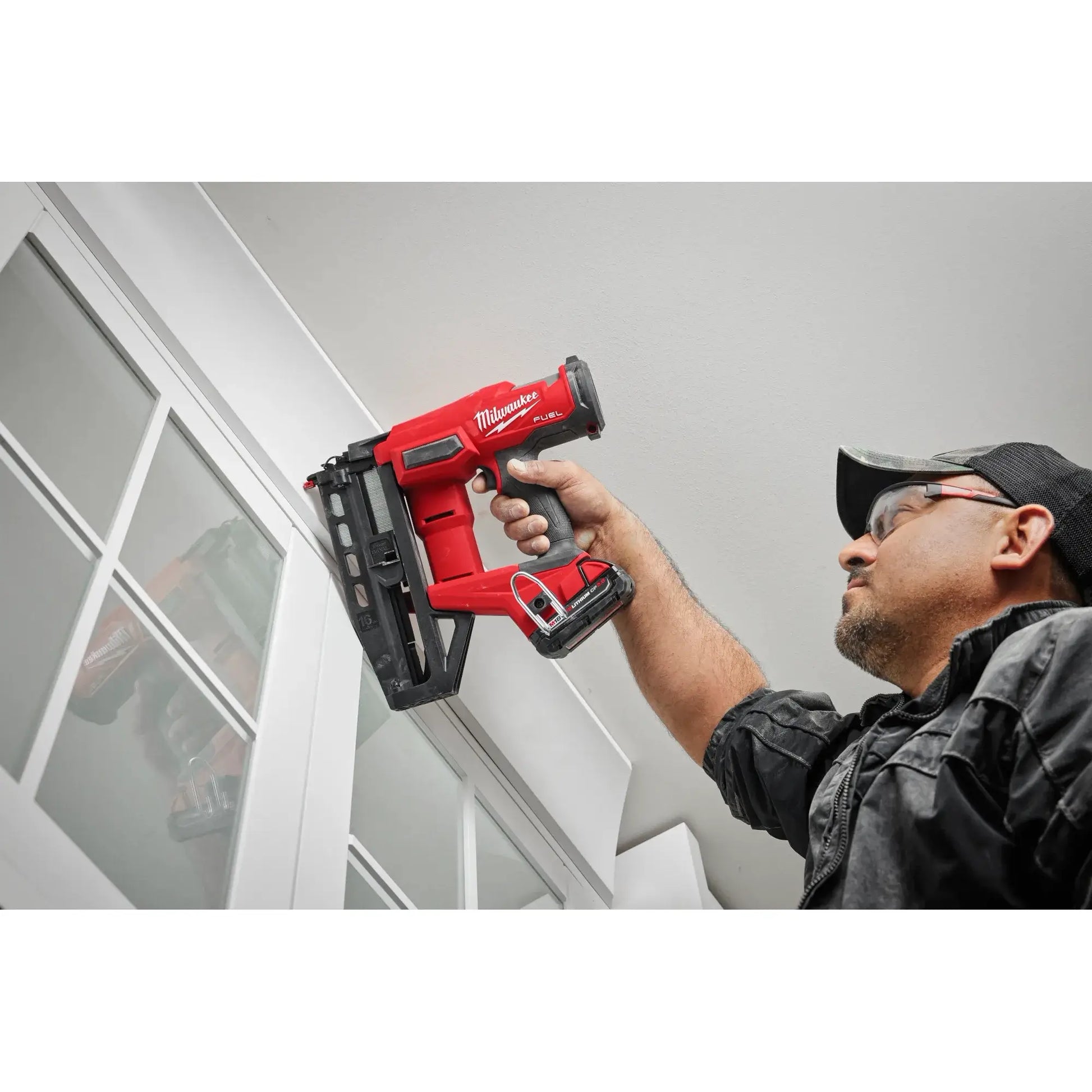 Person using a red Milwaukee nail gun in an indoor setting