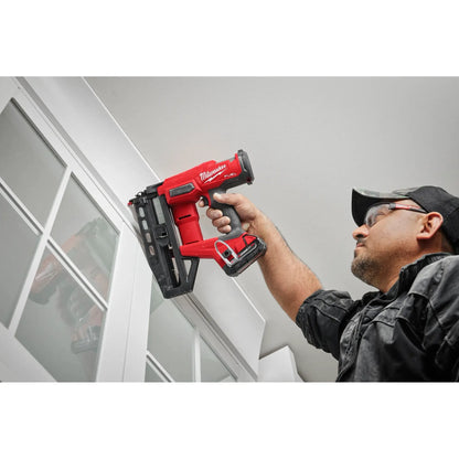 Person using a red Milwaukee nail gun in an indoor setting