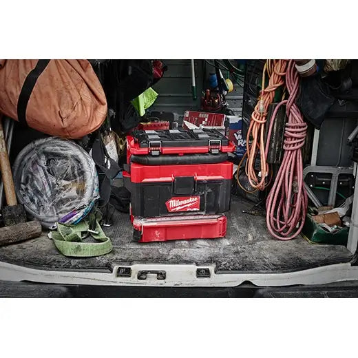 Red Milwaukee toolbox in a cluttered car trunk with various items.