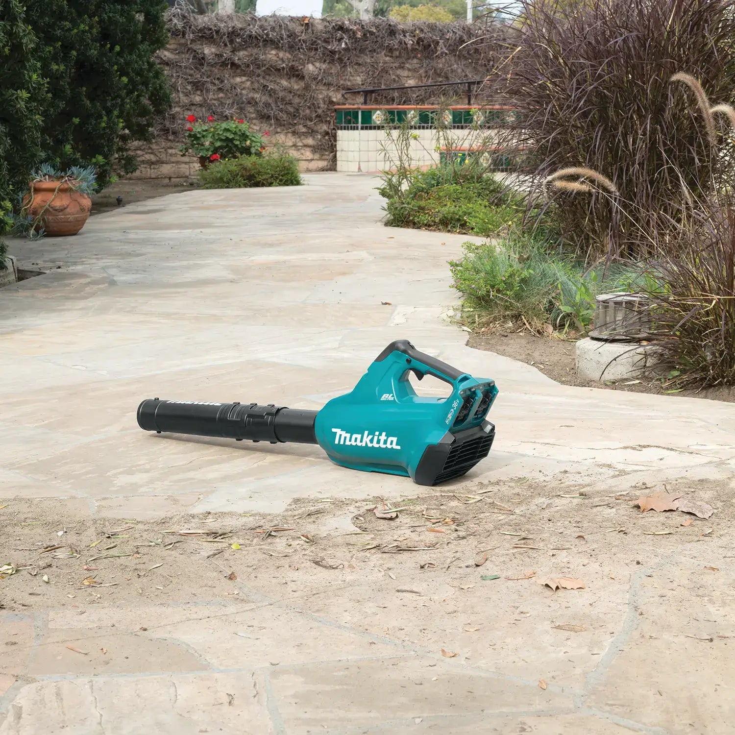 Makita leaf blower on a stone patio with garden background
