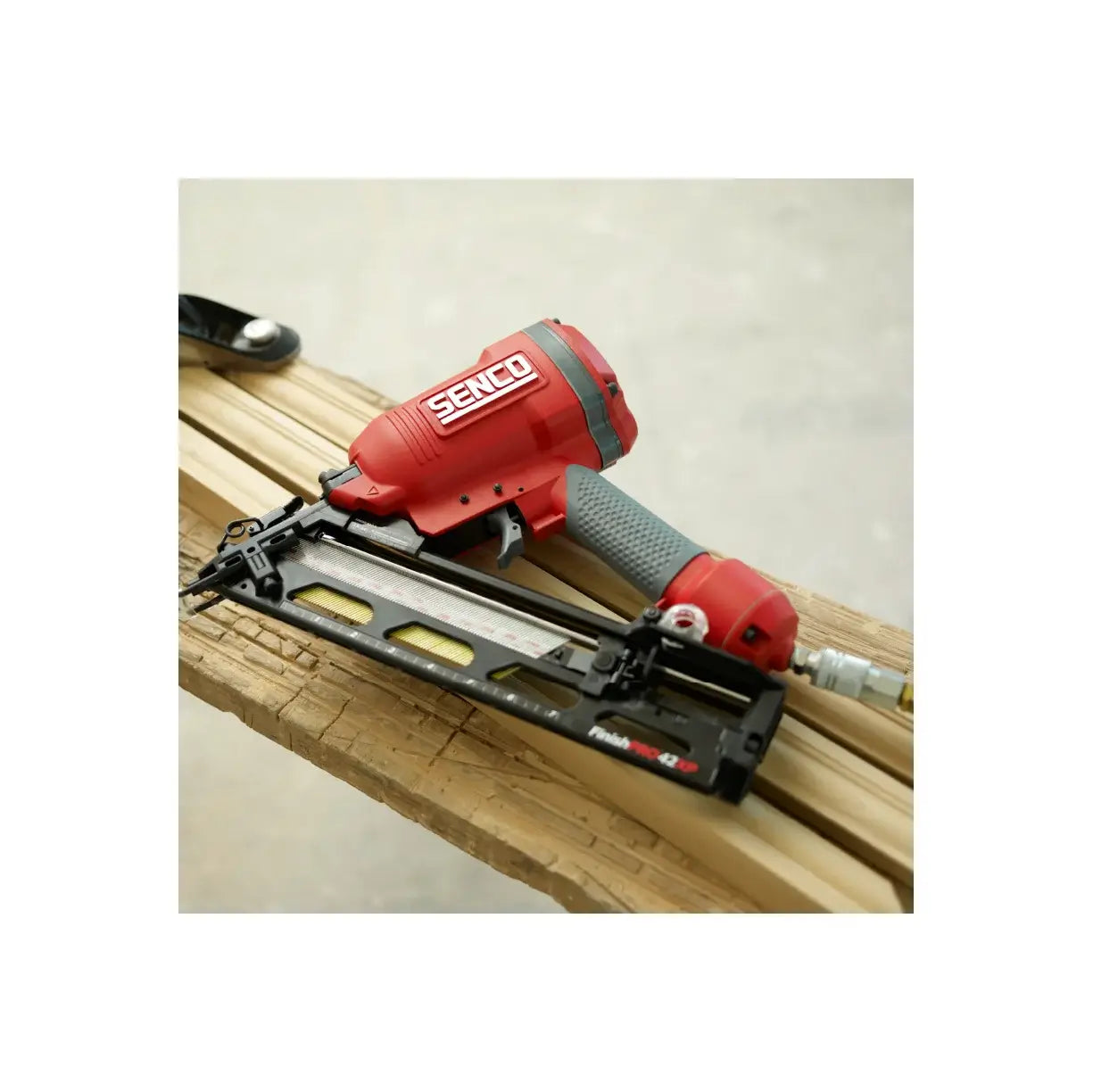 Red Senco nail gun on a wooden surface