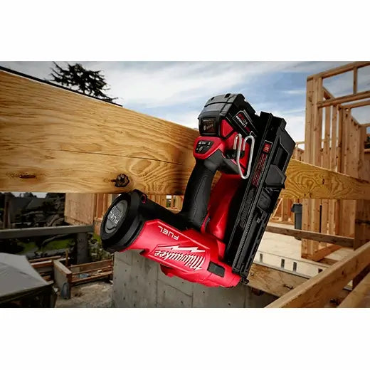 Red and black nail gun on a wooden beam with a construction site background