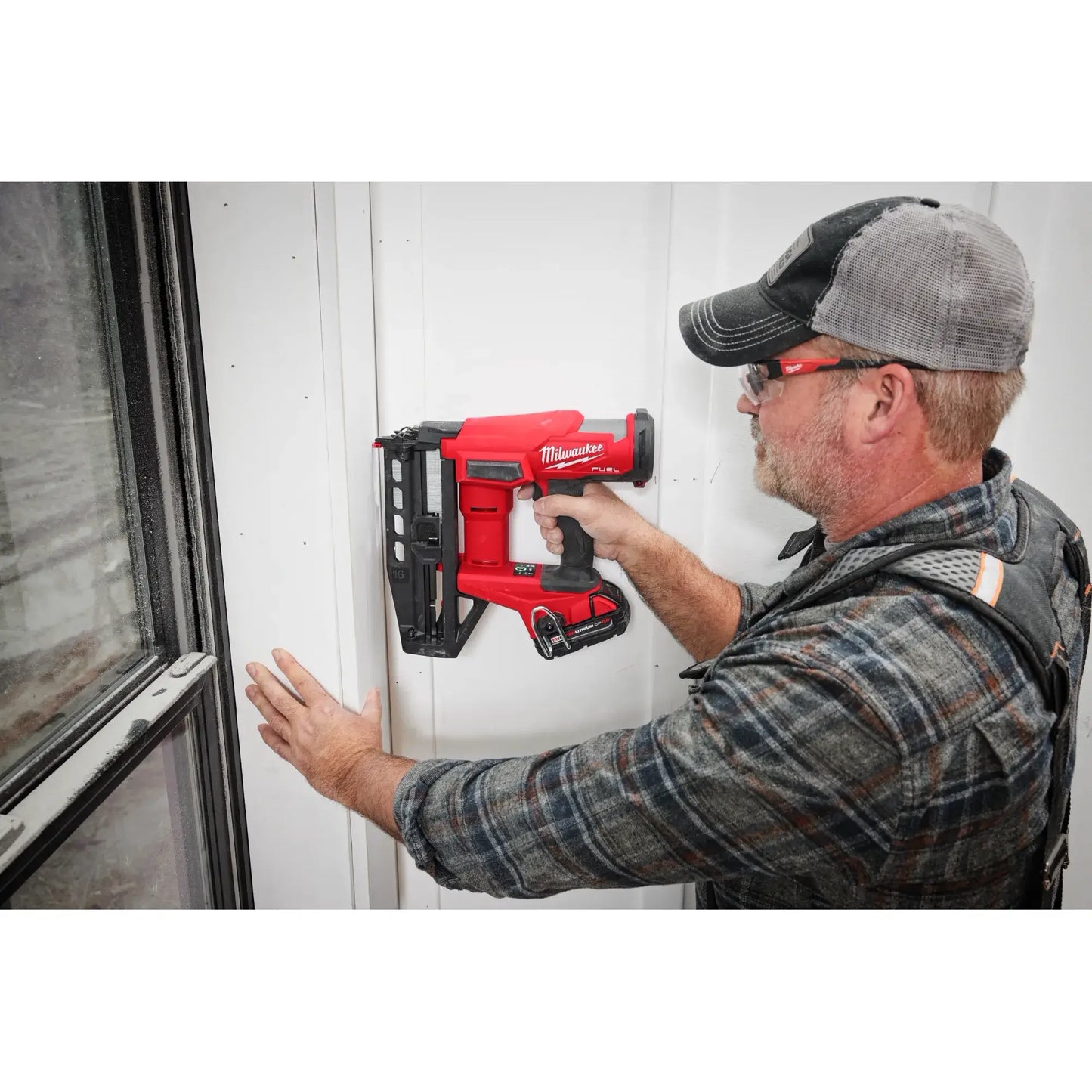 Person using a red power tool on a white wall