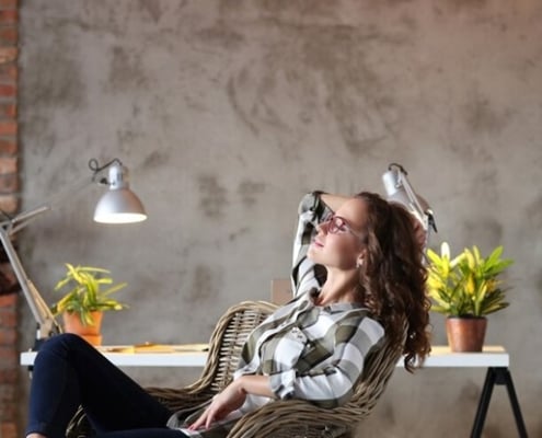 Image of a woman sitting back in her chair in front of a white desk